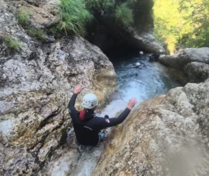 Person sliding down a natural rock toboggan in Sušec Canyon surrounded by steep canyon walls.