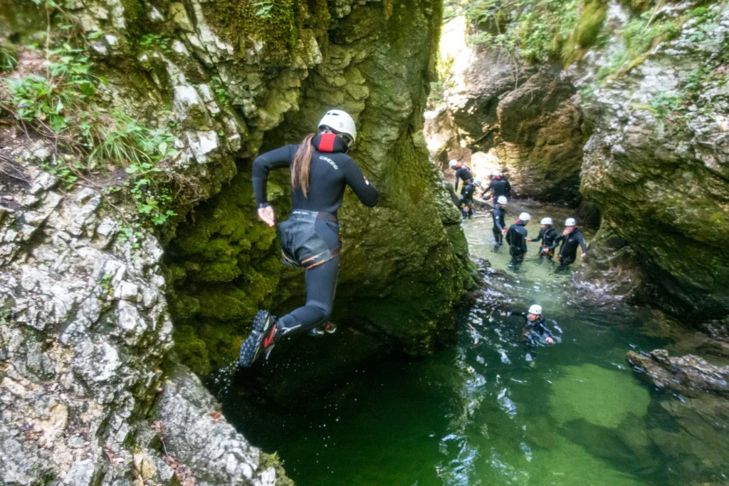 Canyoning jump into emerald pool in Grmecica Canyon Slovenia