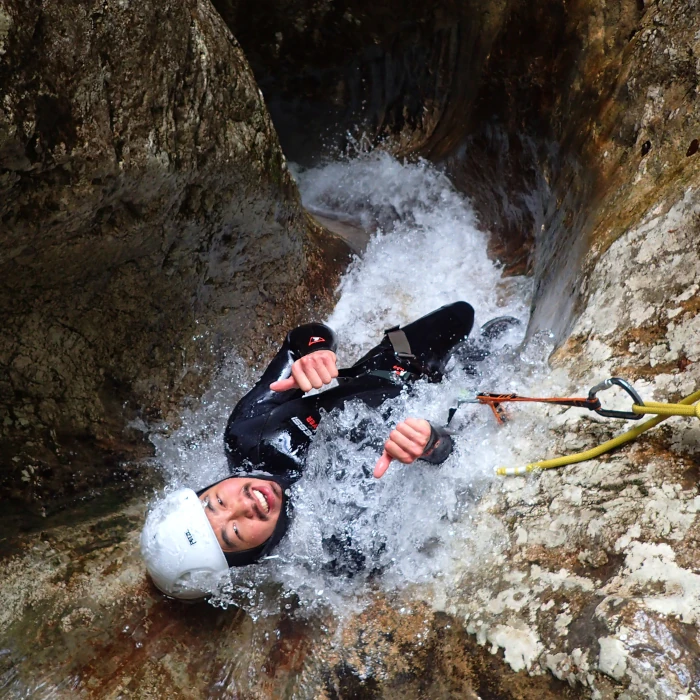 Canyoner sliding down a narrow waterfall chute in Jerečica Canyon, Slovenia