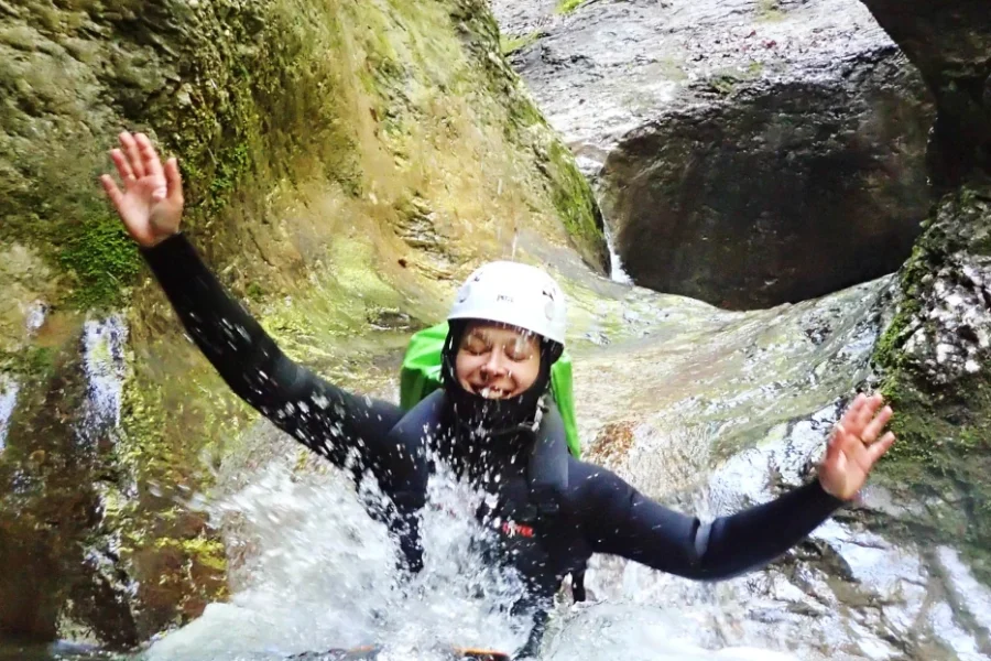 Smiling canyoneer sliding into water during Jerečica canyoning tour